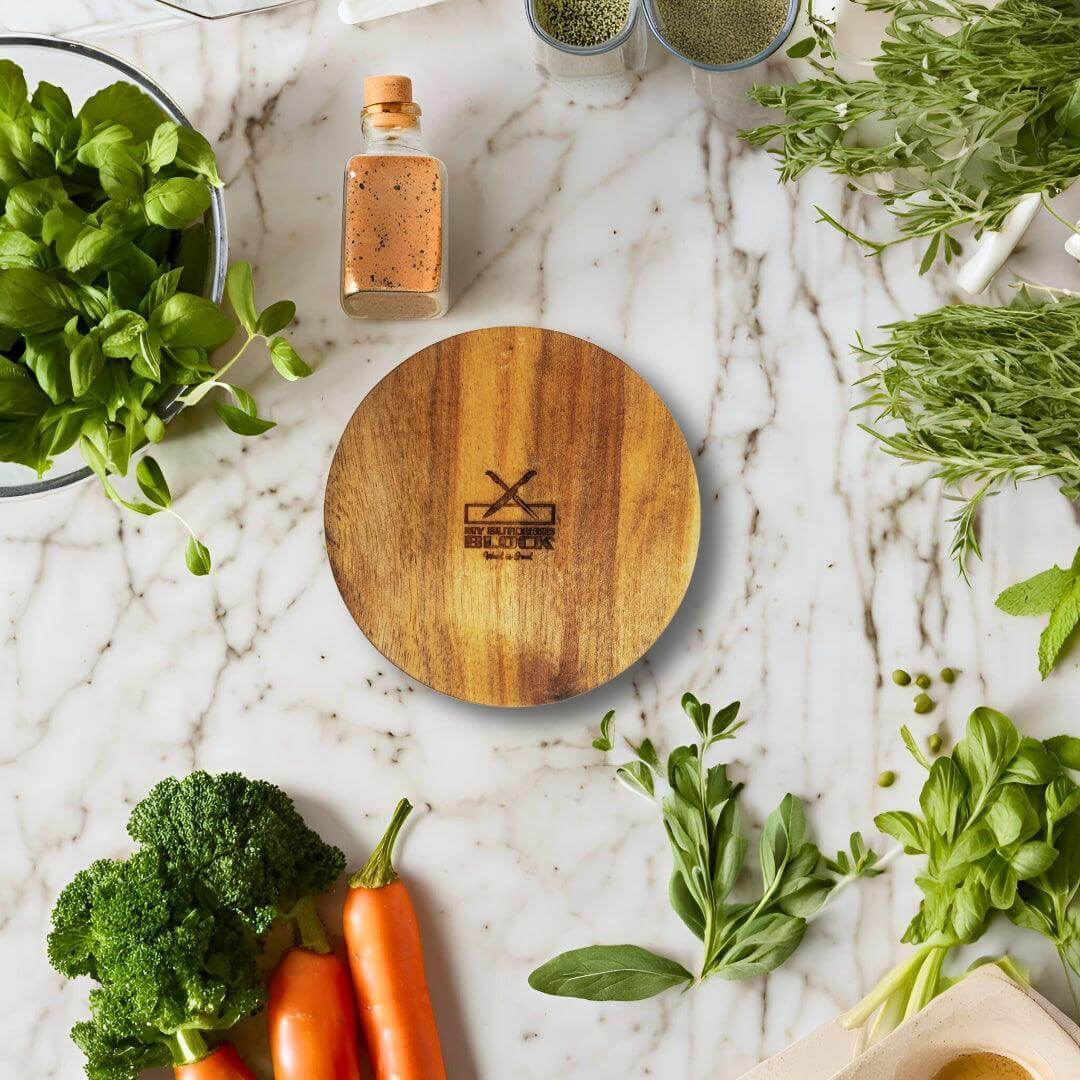 Wooden salt and pepper holder on a marble countertop surrounded by fresh herbs and vegetables.