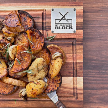 Roasted vegetables garnished with rosemary on a wooden cutting board from My Butchers Block.
