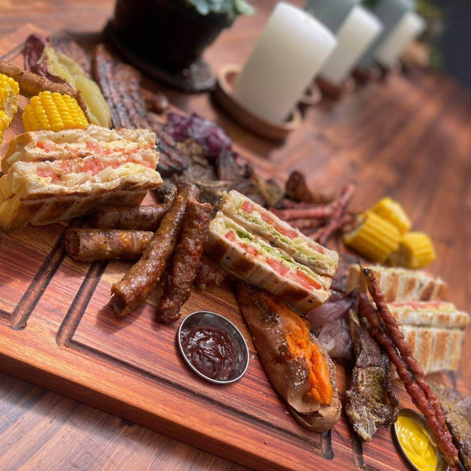 A large Shisanyama Plankie Braai Board featuring grilled meats, corn, and sandwiches, perfect for a braai feast.