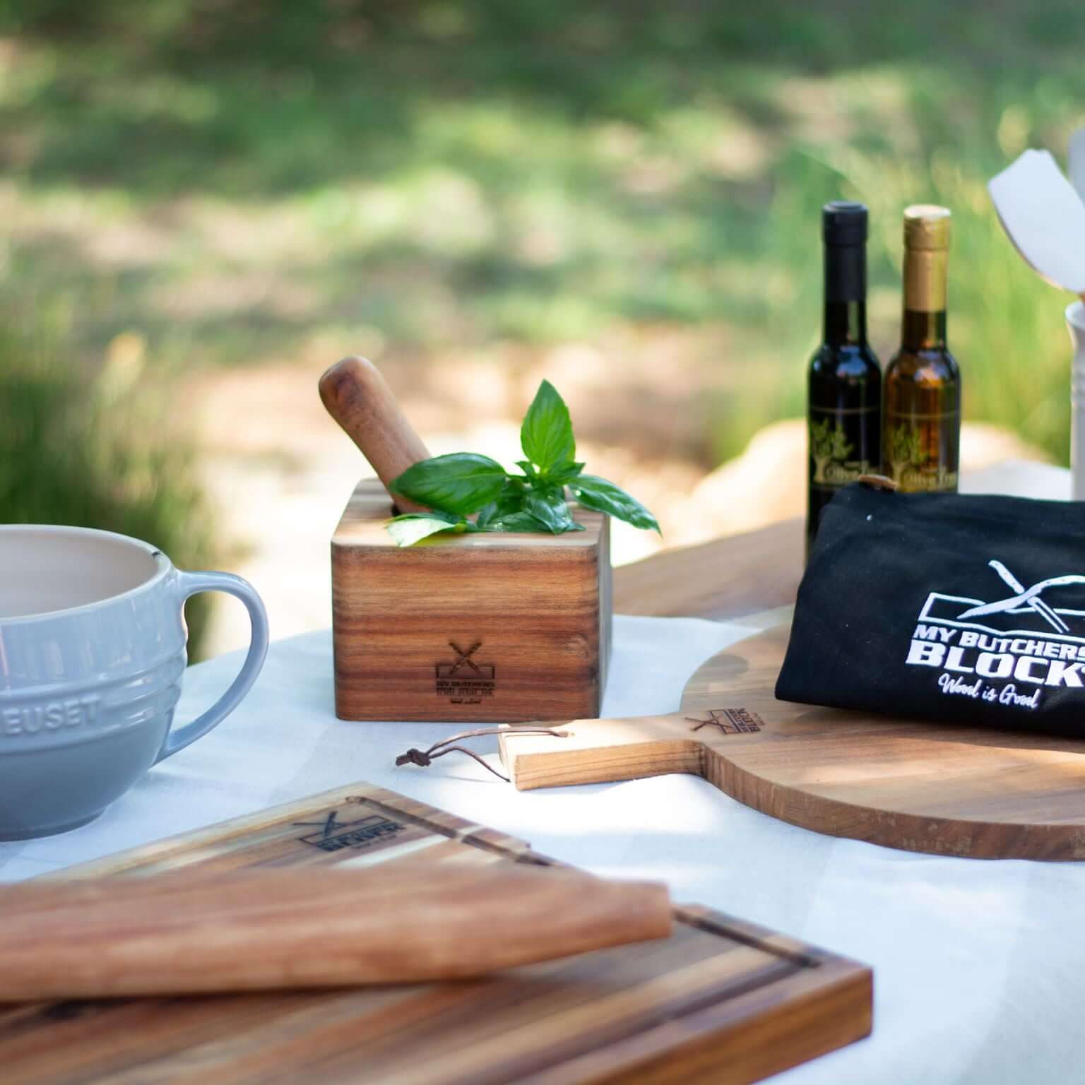 Beautiful acacia wood pestle and mortar surrounded by kitchen essentials for cooking and preparing gourmet dishes.