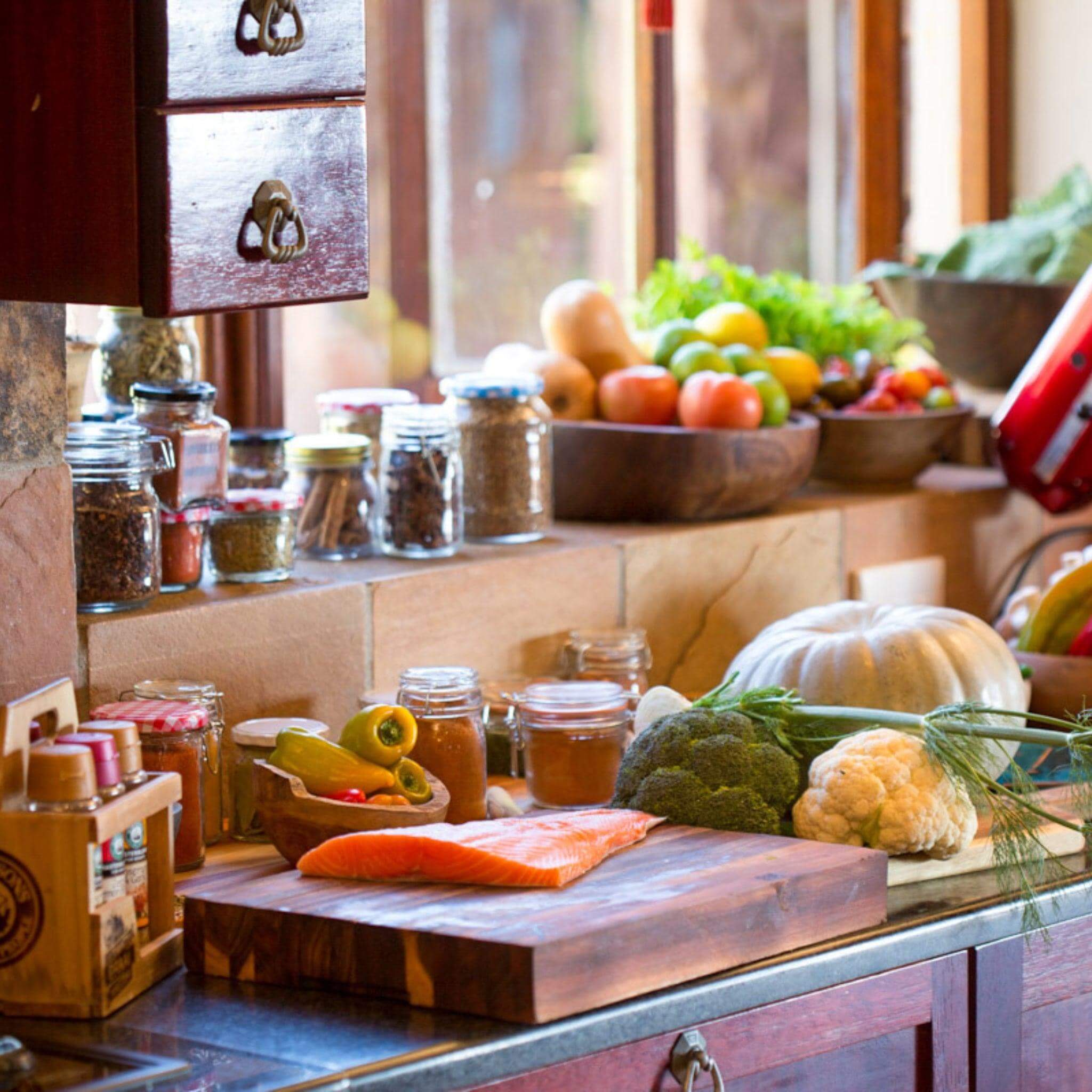 Large chopping block with fresh vegetables and spices in a rustic kitchen setting.