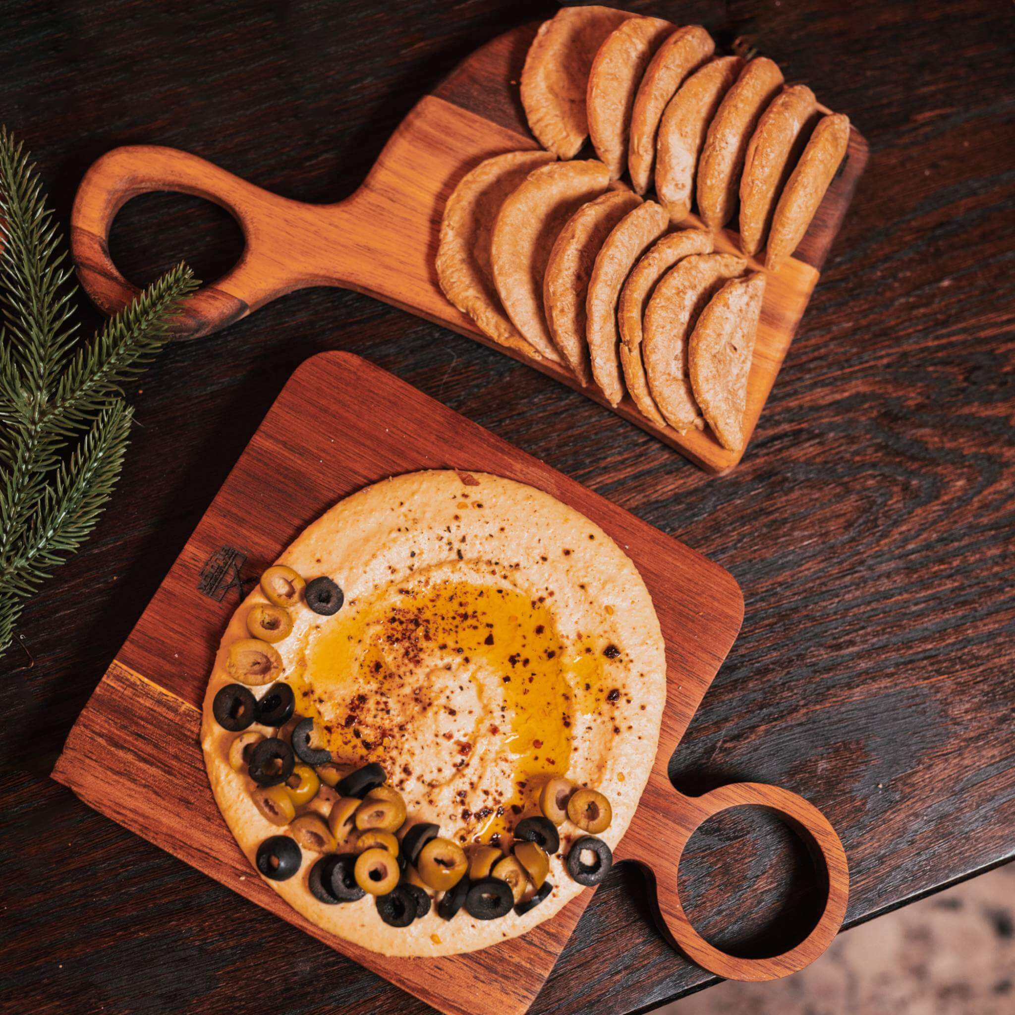 Stylish Nesting Board Set Small with hummus and olives, perfect for serving snacks and gourmet dishes.