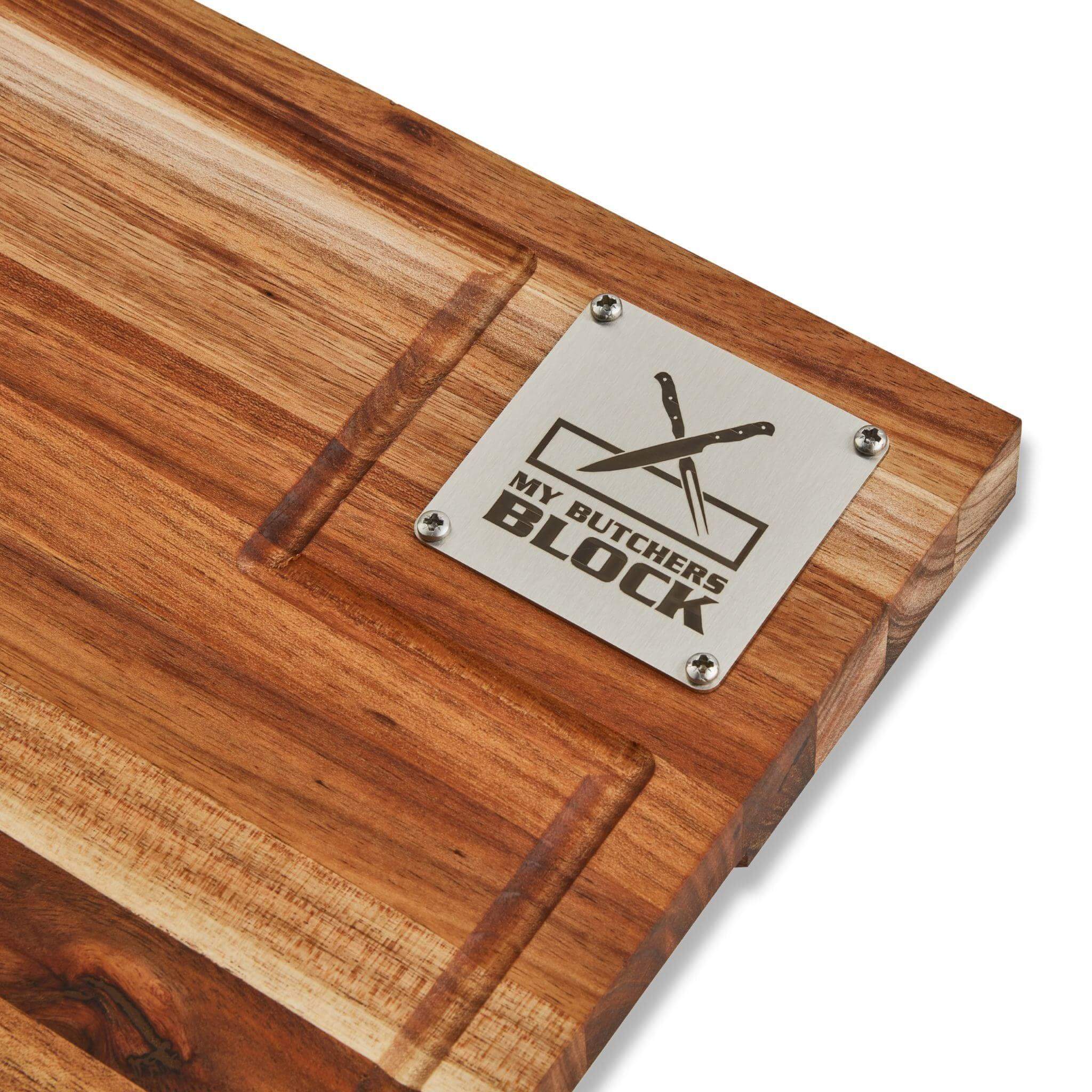 Close-up of My Butcher's Block chopping board showcasing the metal logo and rich acacia wood grain.