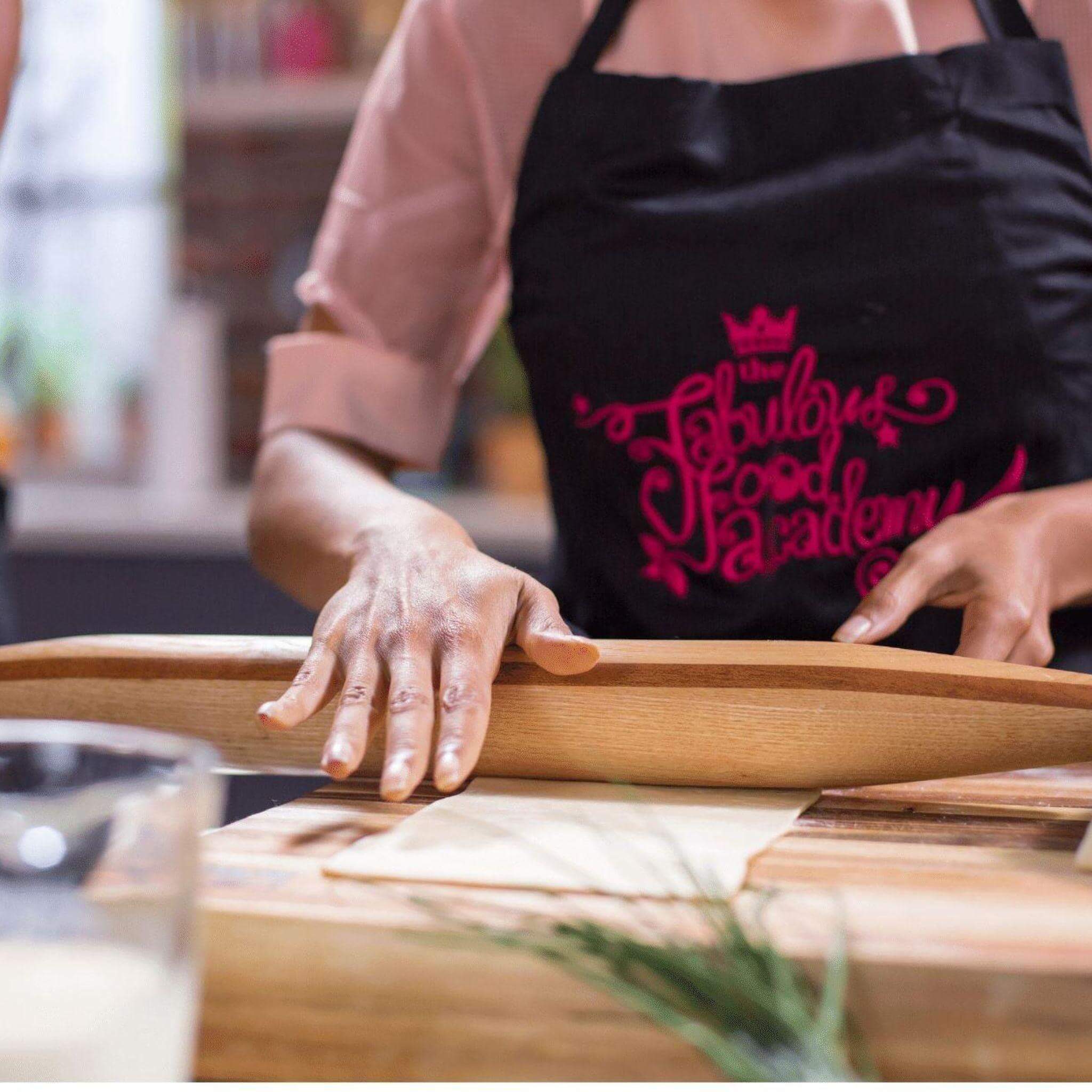 Person using a French rolling pin on a wooden countertop, showcasing pastry preparation in a stylish kitchen.