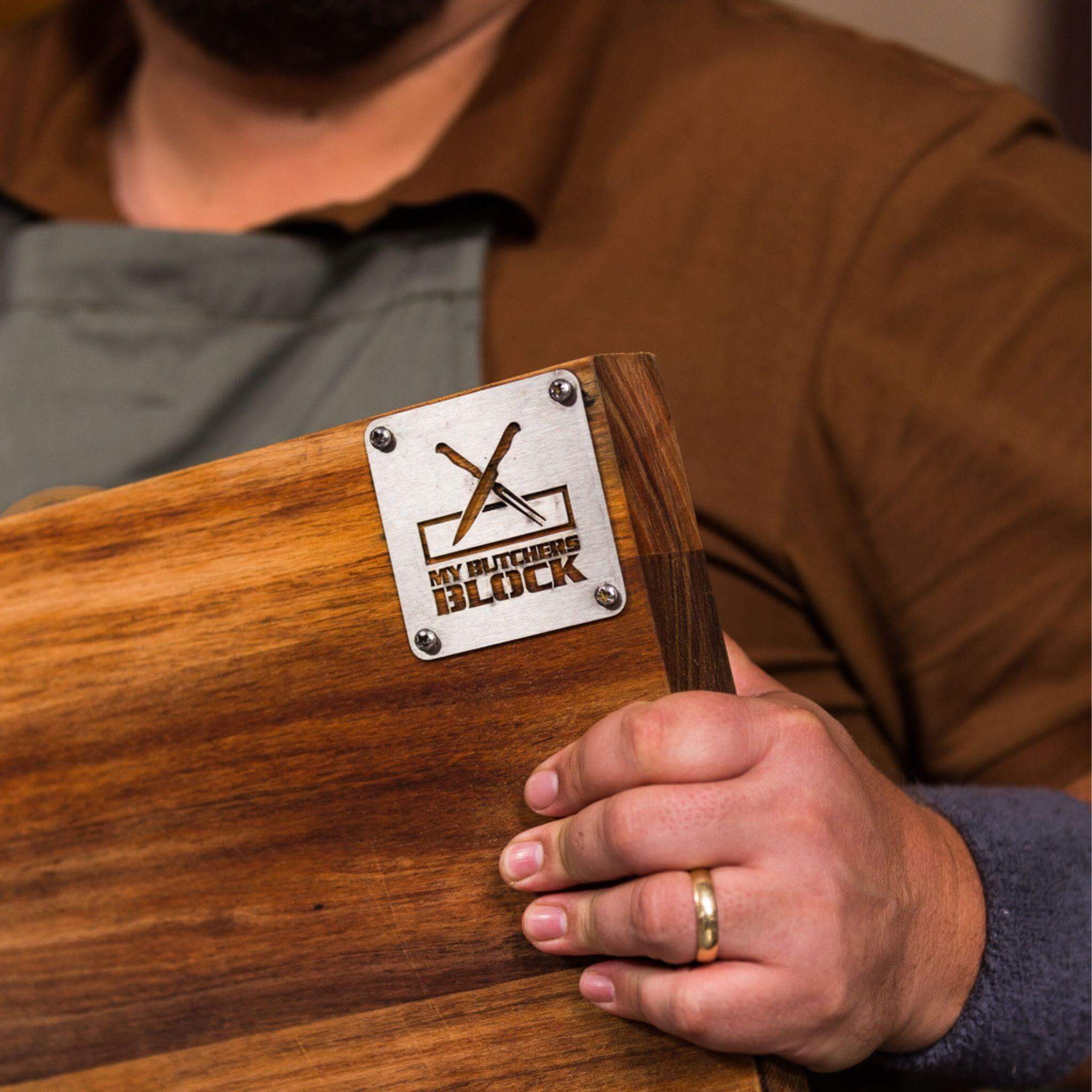 Person holding a Grand Daddy chopping block showcasing sturdy design and engraved logo, ideal for braai and serving.