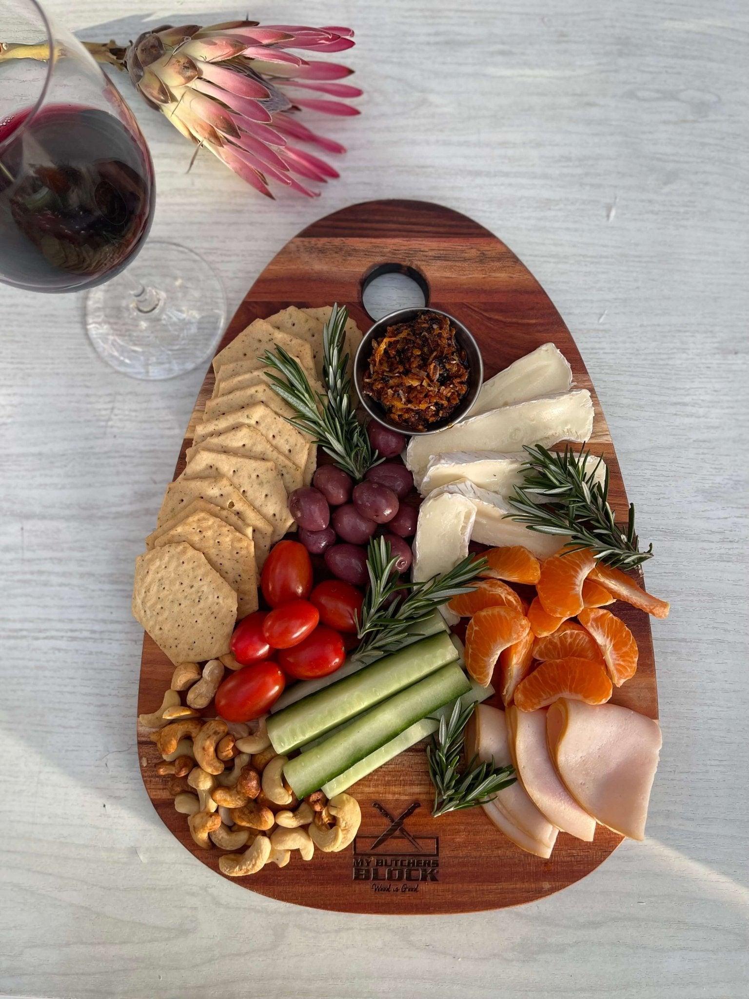 Charcuterie spread on an old design paddle board, featuring cheeses, crackers, fruits, and vegetables, perfect for hosting.