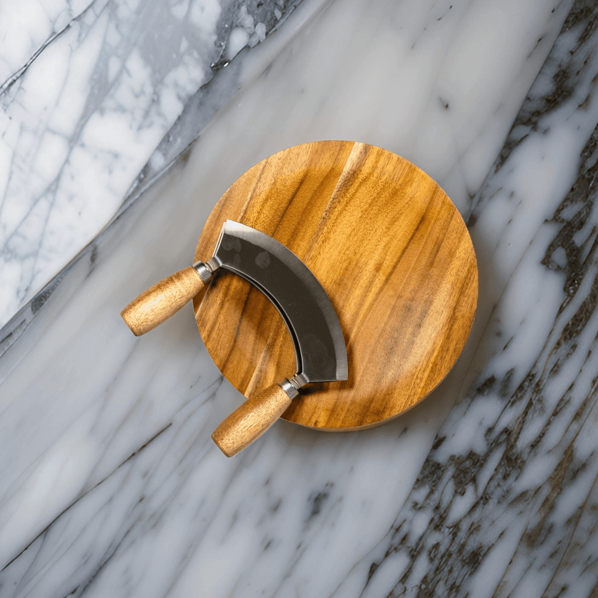 Mezzaluna herb chopper on a wooden board atop marble surface, showcasing ergonomic design.