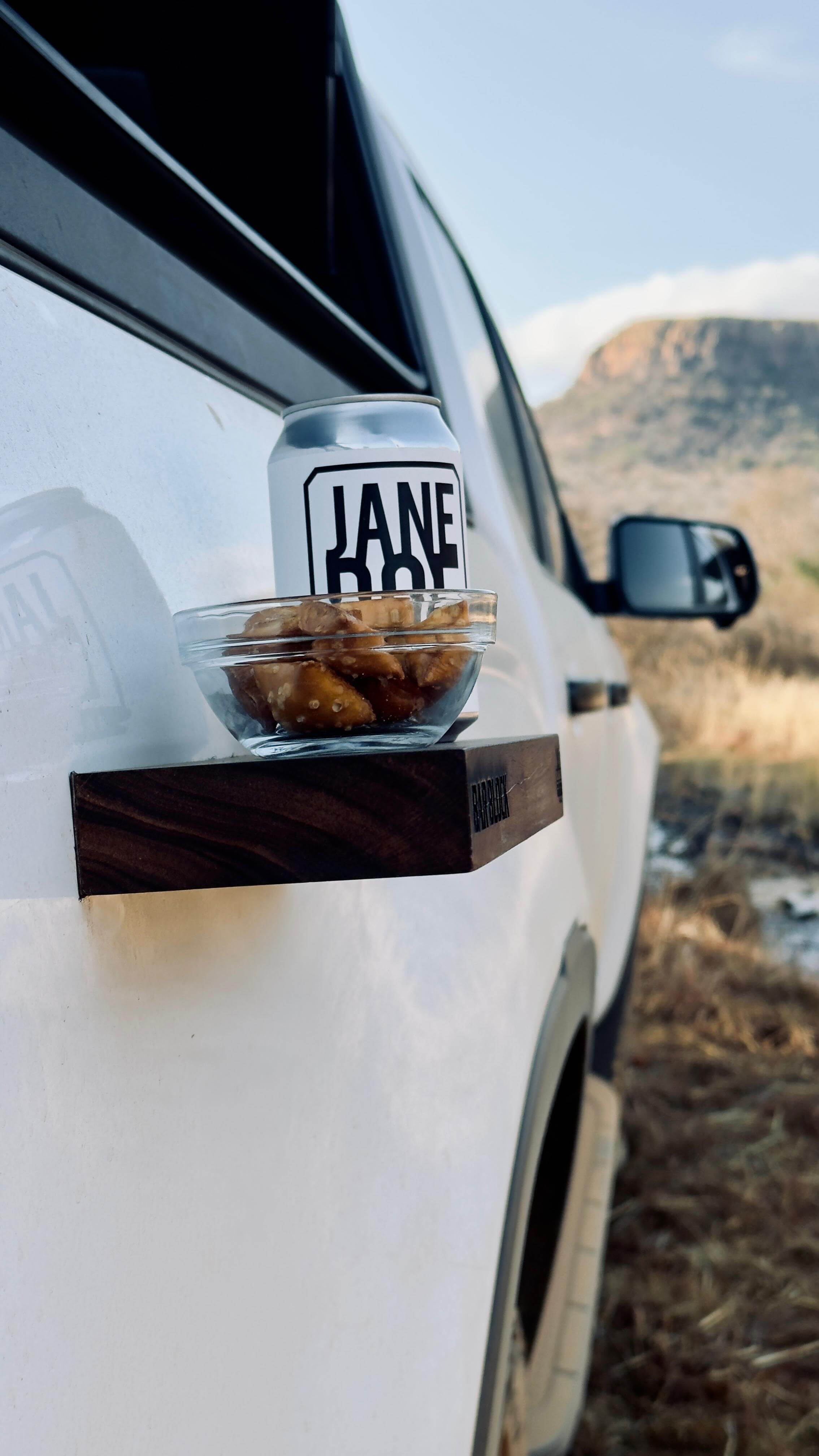 The Bar Block serving snacks and drinks on a vehicle, highlighting a wooden chopping board for outdoor use.