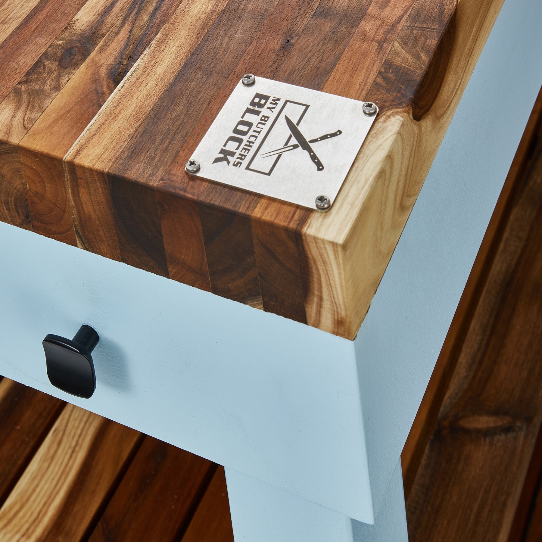 Close-up of Butcher's Bench solid wood top with logo and drawer handle, showcasing durable design for kitchen prep.