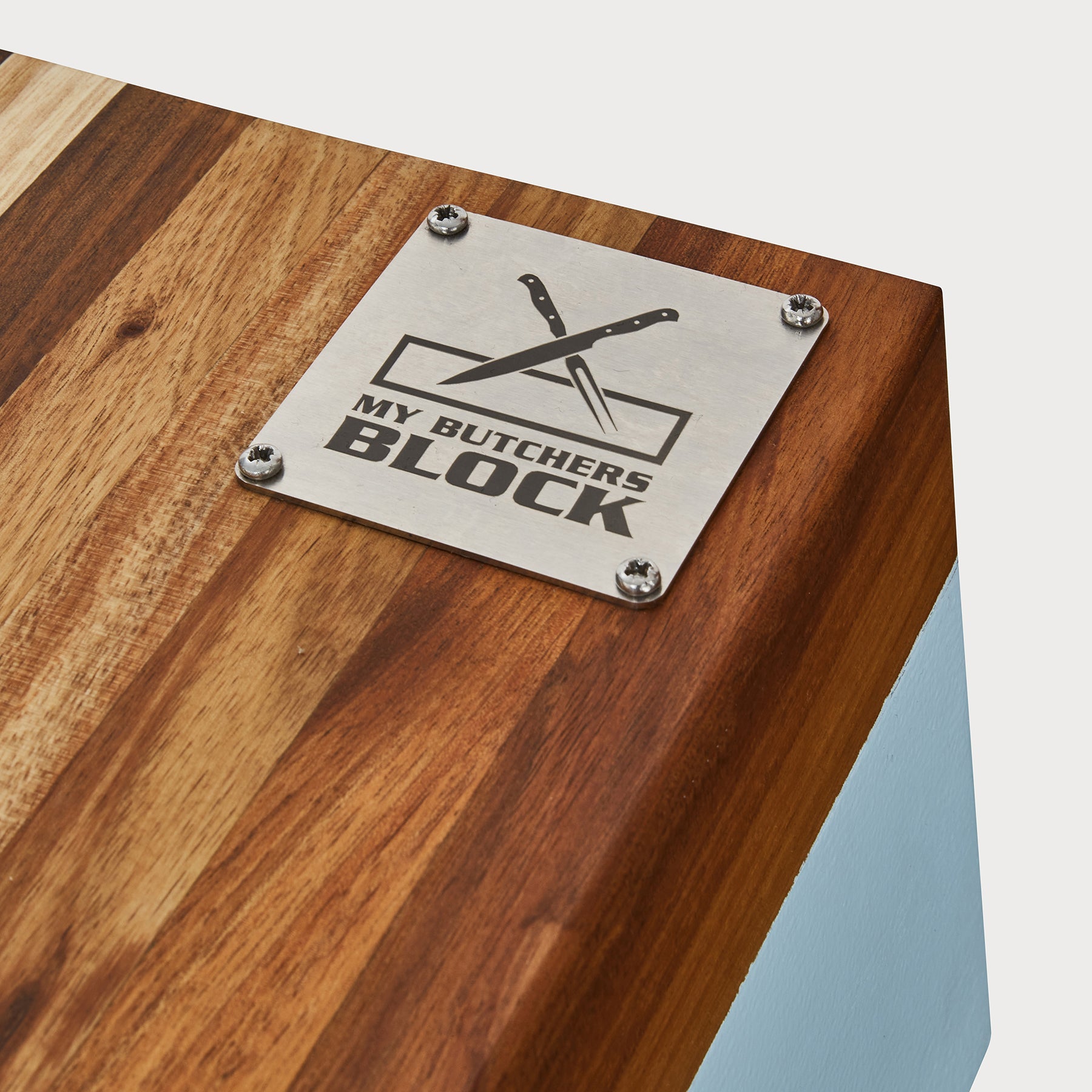 Close-up of a butcher block top featuring a metal plaque with the inscription 'My Butcher's Block' and knife graphic.