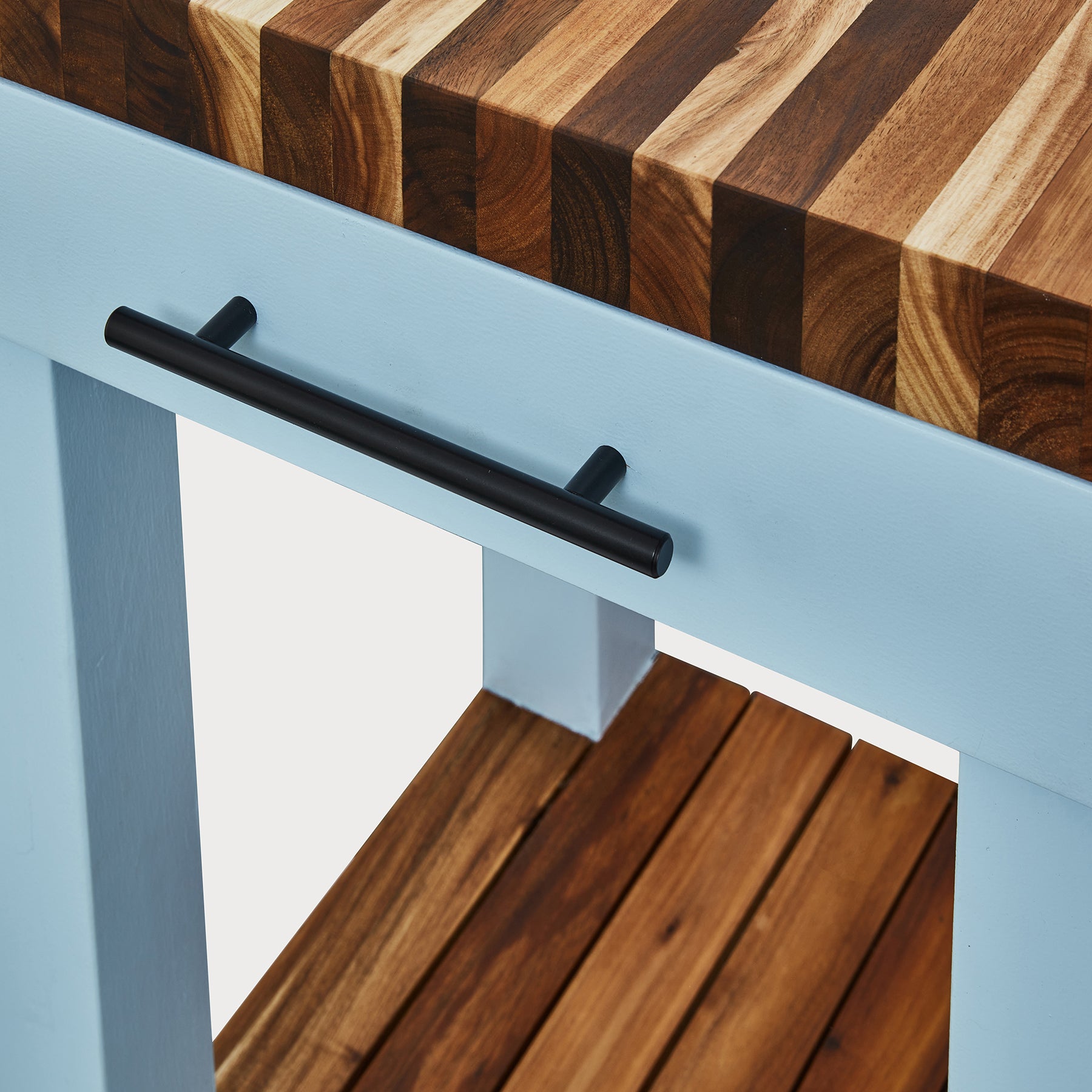 Close-up of Butcher’s Bench showing solid wood top and black handle on compact prep station.