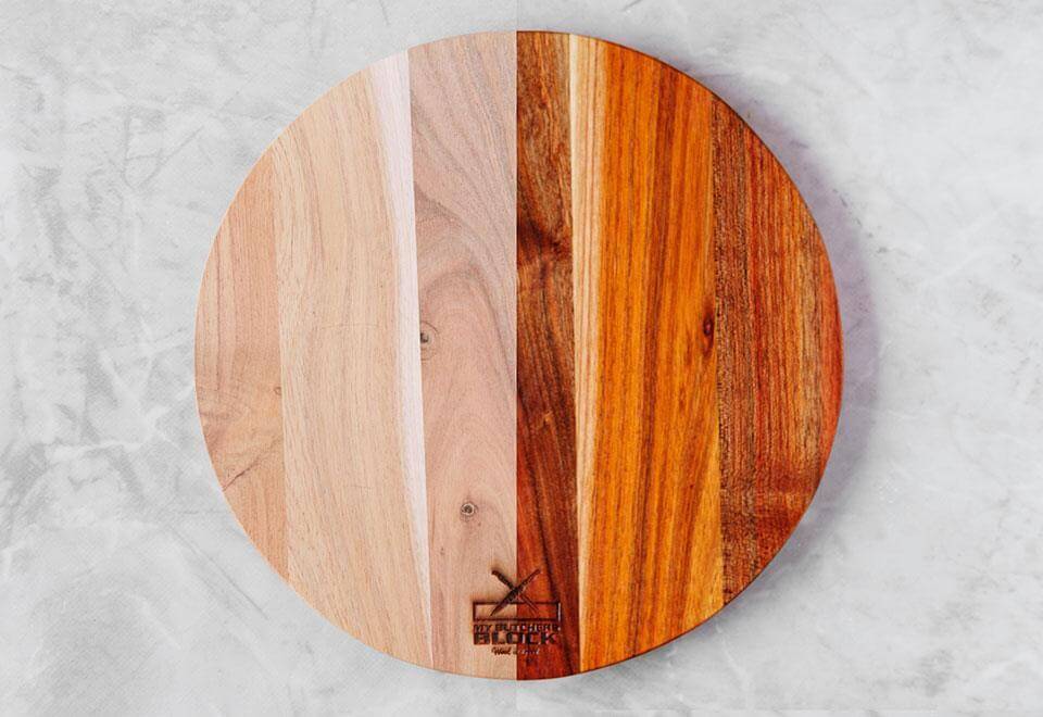 Round wooden cutting board with a mix of light and dark wood grains, showcasing natural beauty and craftsmanship.