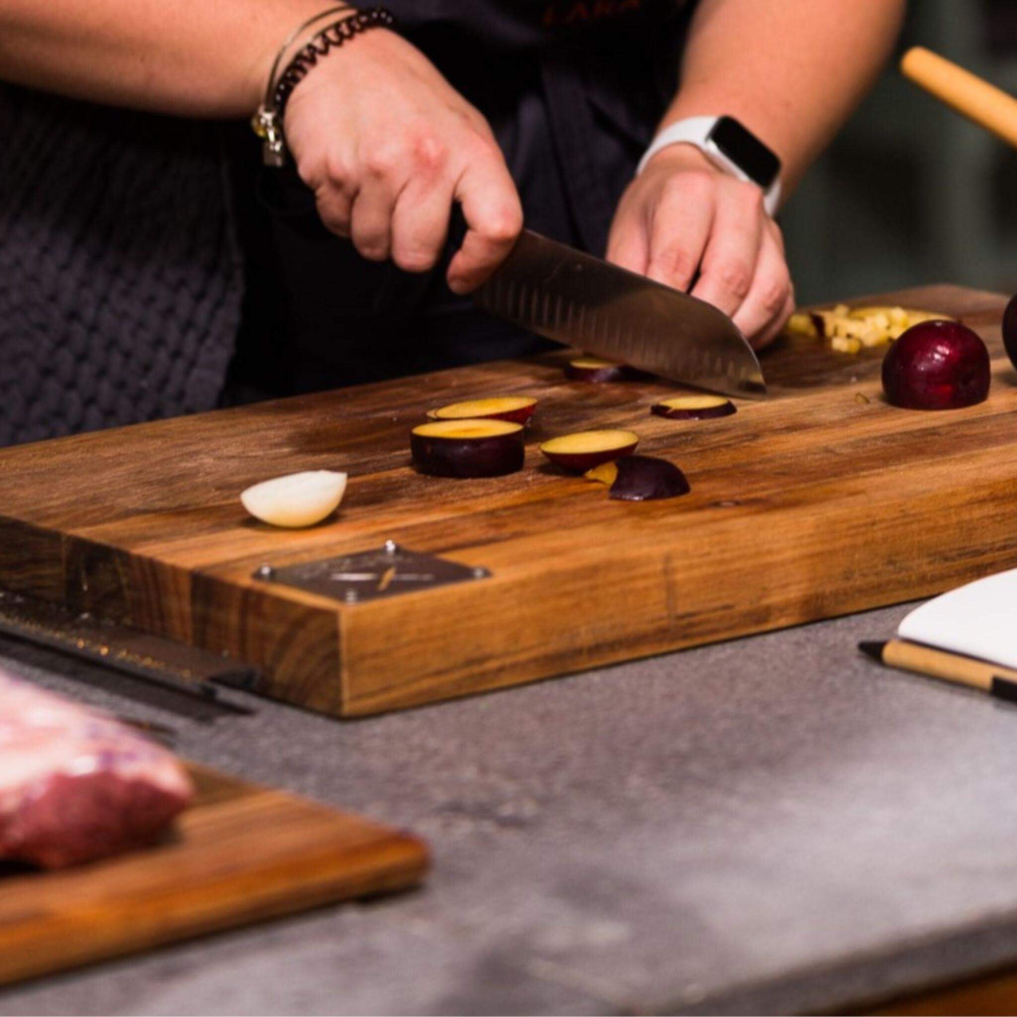 Person slicing vegetables on a Grand Daddy chopping block in a kitchen setting.