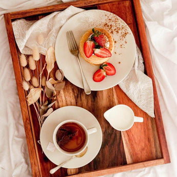 Elegant serving tray with pancake, strawberries, and tea cup on a cozy surface.
