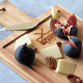 Cheese platter with figs, cheese, pecans, and a knife on a wooden board, perfect for entertaining.