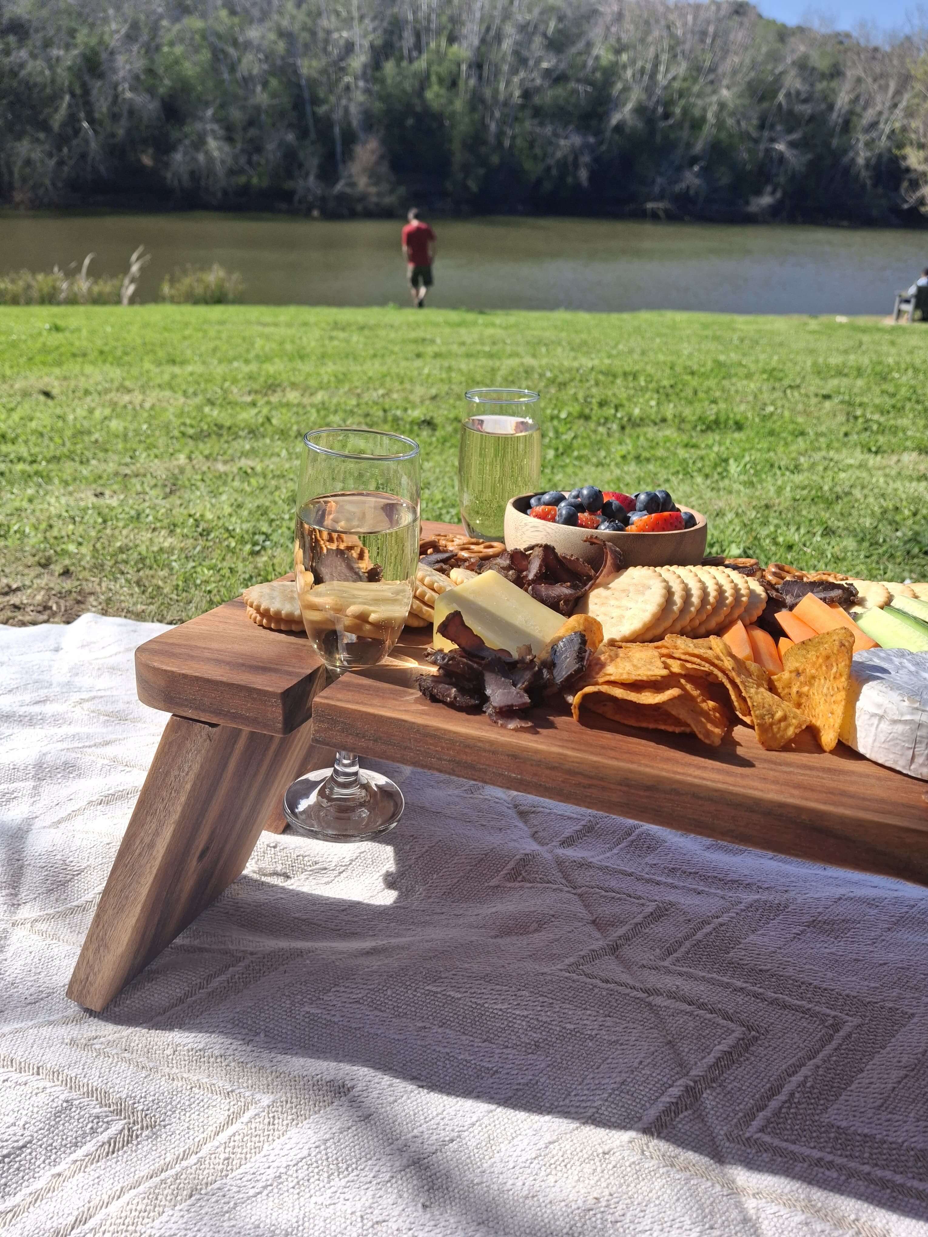 Elegant grazing table outdoors with snacks and drinks, perfect for stylish entertaining by the water.