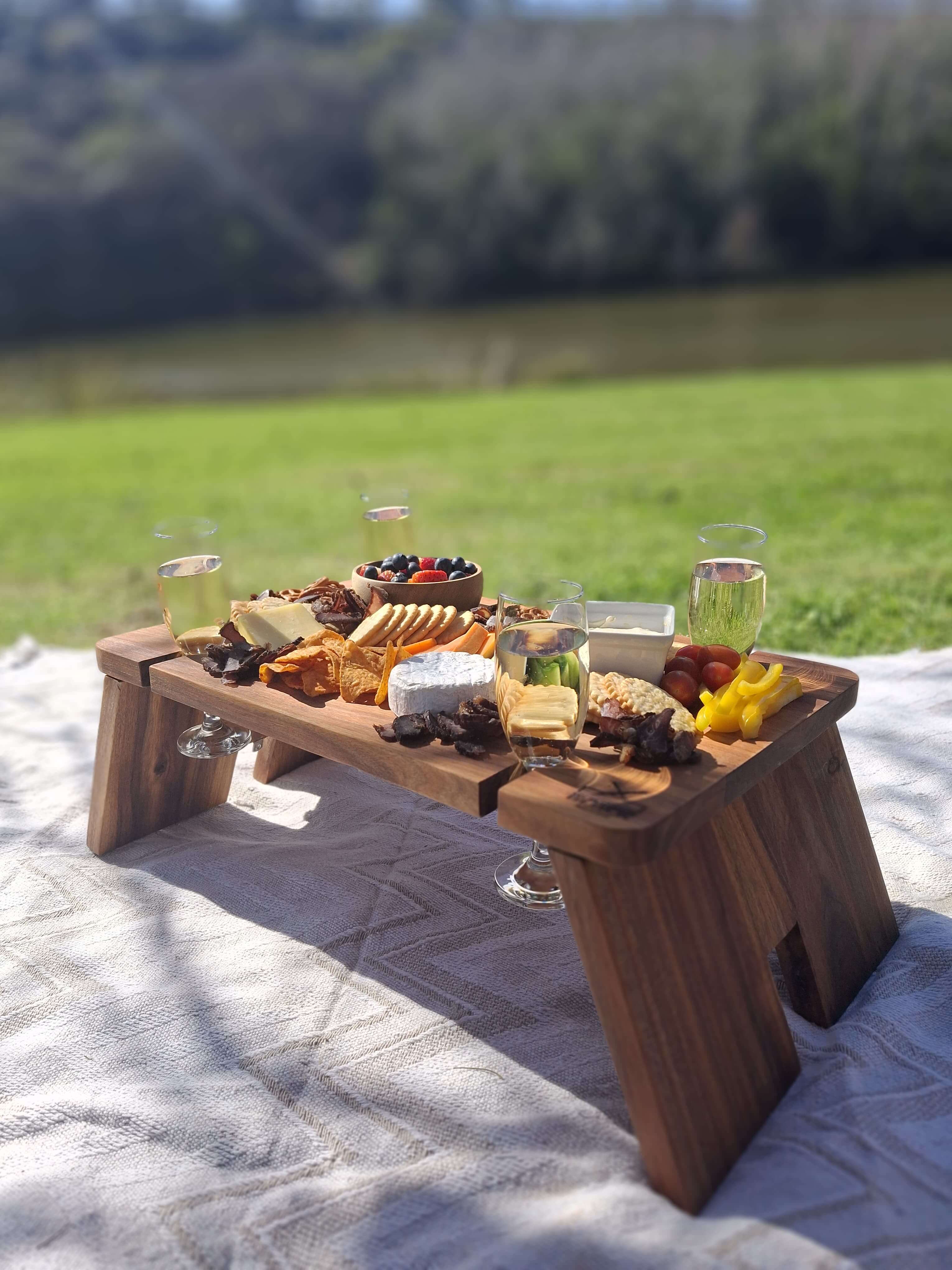 Stylish My Butchers Block Grazing Table set with gourmet snacks and drinks outdoors by a scenic view.