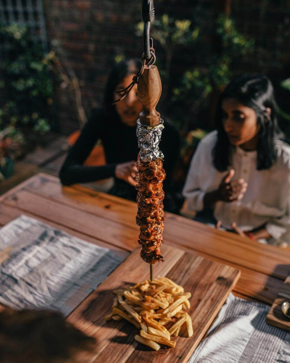 Single skewer with grilled meat and fries, perfect for outdoor cooking and entertaining with style.