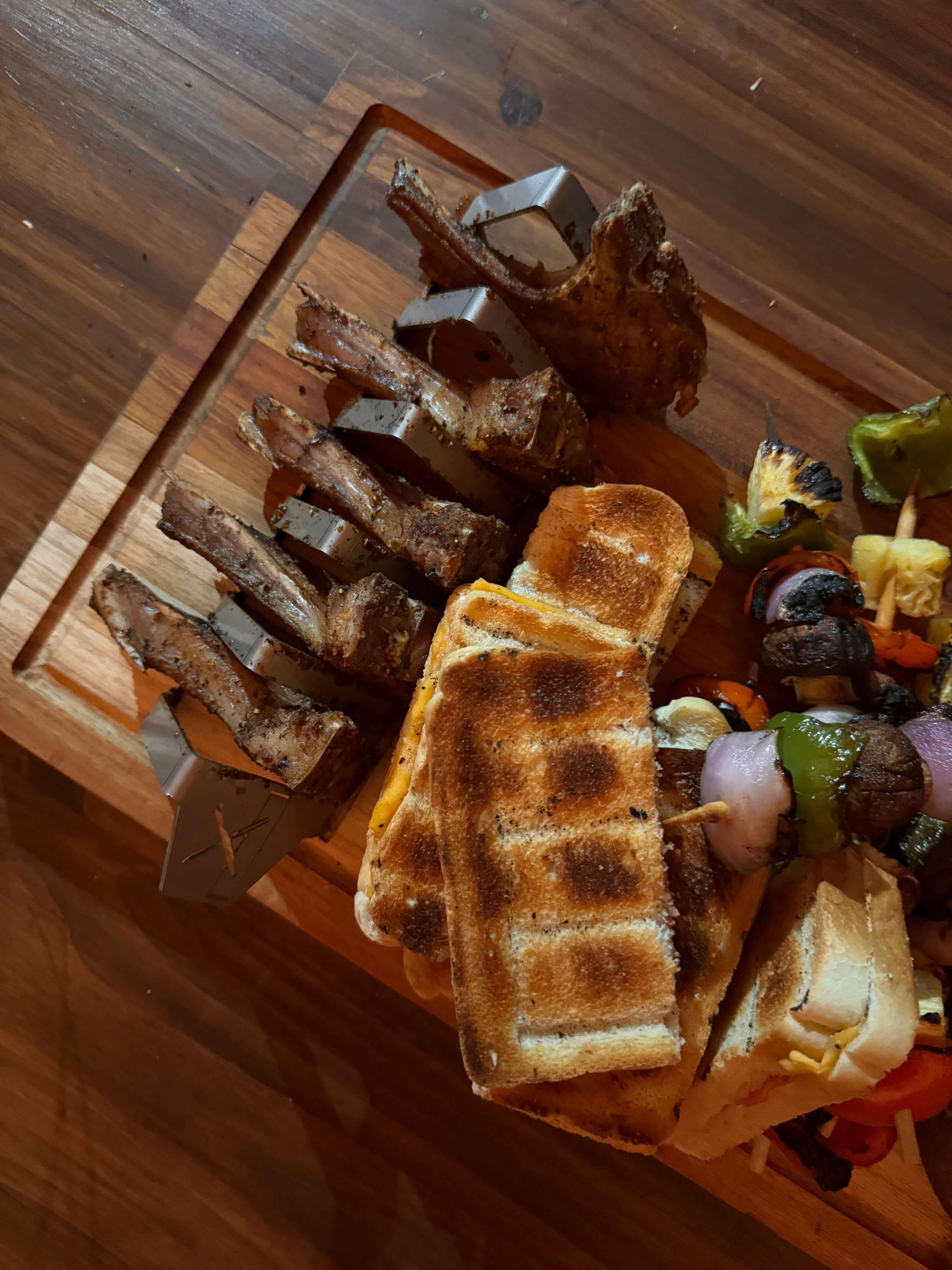Braai and Slice Master Block with grilled ribs and toasted bread on a wooden cutting board.