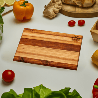 Basic Chopping Board Medium on a kitchen countertop surrounded by fresh vegetables and herbs.