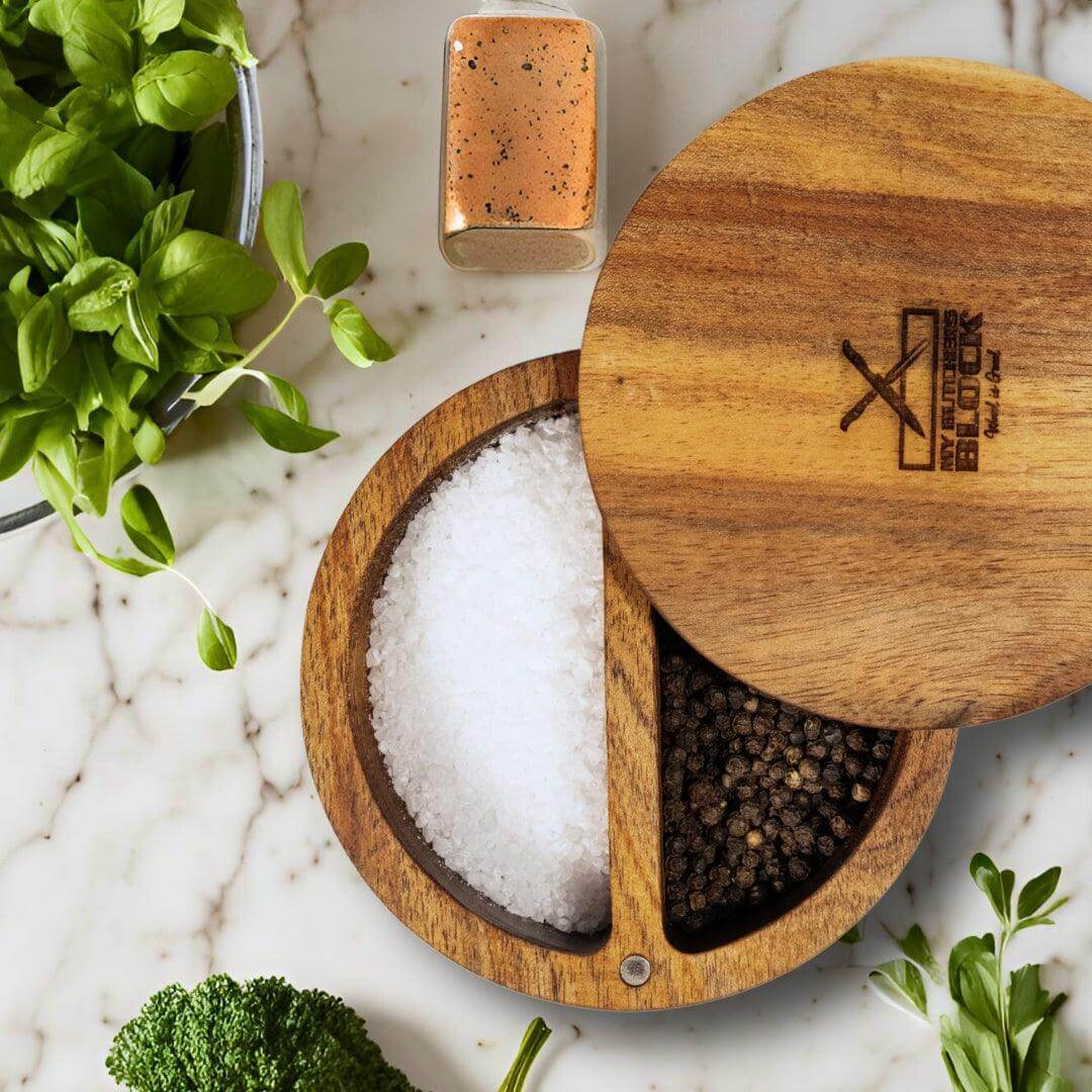 Stylish salt and pepper holder with dual compartments for convenient seasoning and magnetic lid, placed on a marble surface.