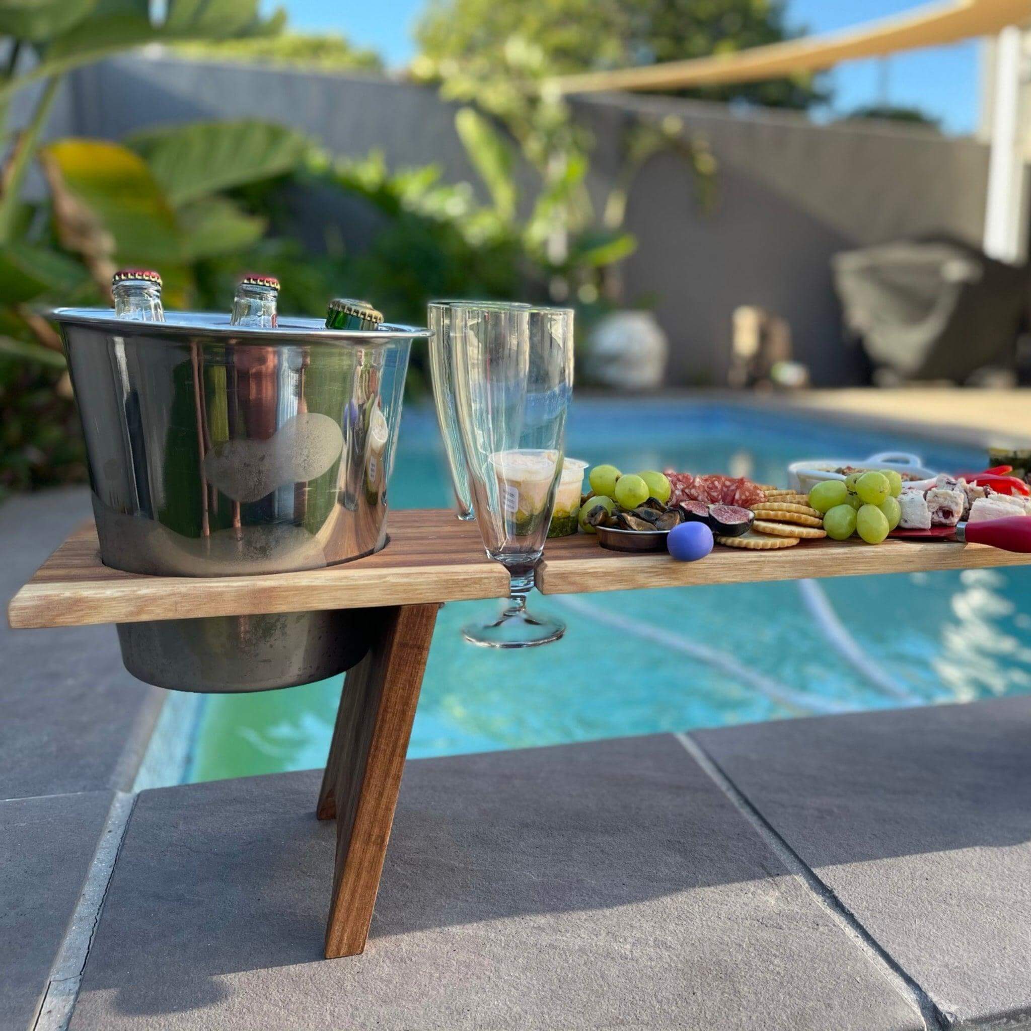 Stylish picnic table with snacks and drinks by the pool, perfect for outdoor dining and gatherings.
