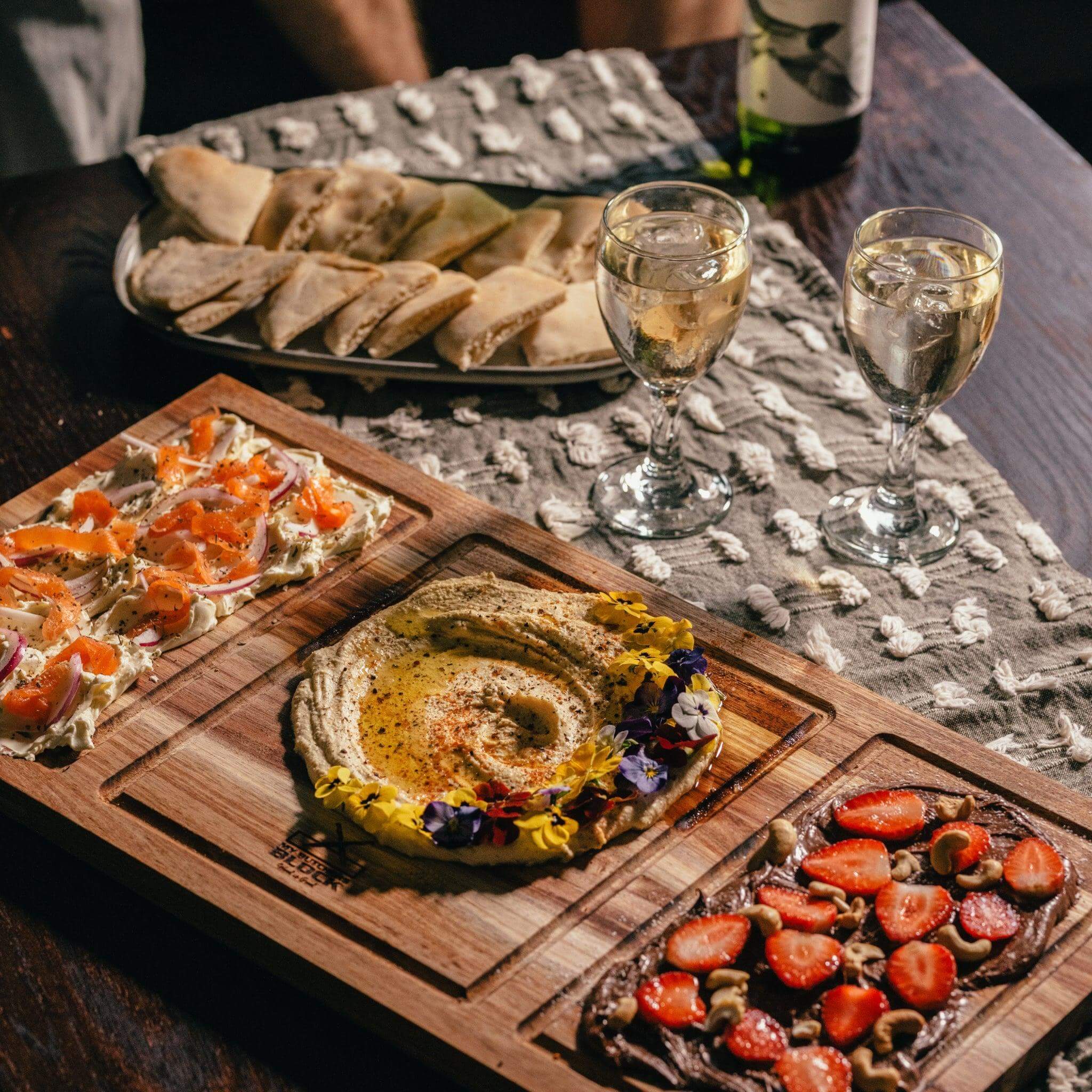 Beautifully plated appetizers and drinks on a wooden serving board, perfect for entertaining guests.