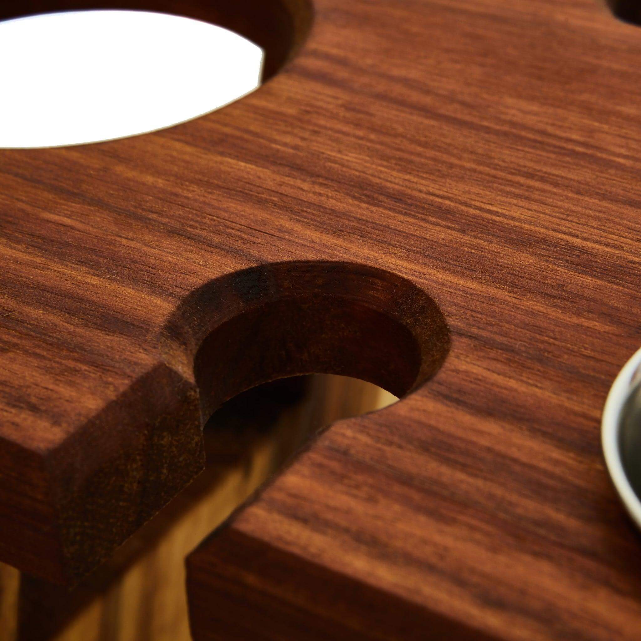 Close-up of a wooden table with a hole for drinks, highlighting craftsmanship and design for outdoor dining.