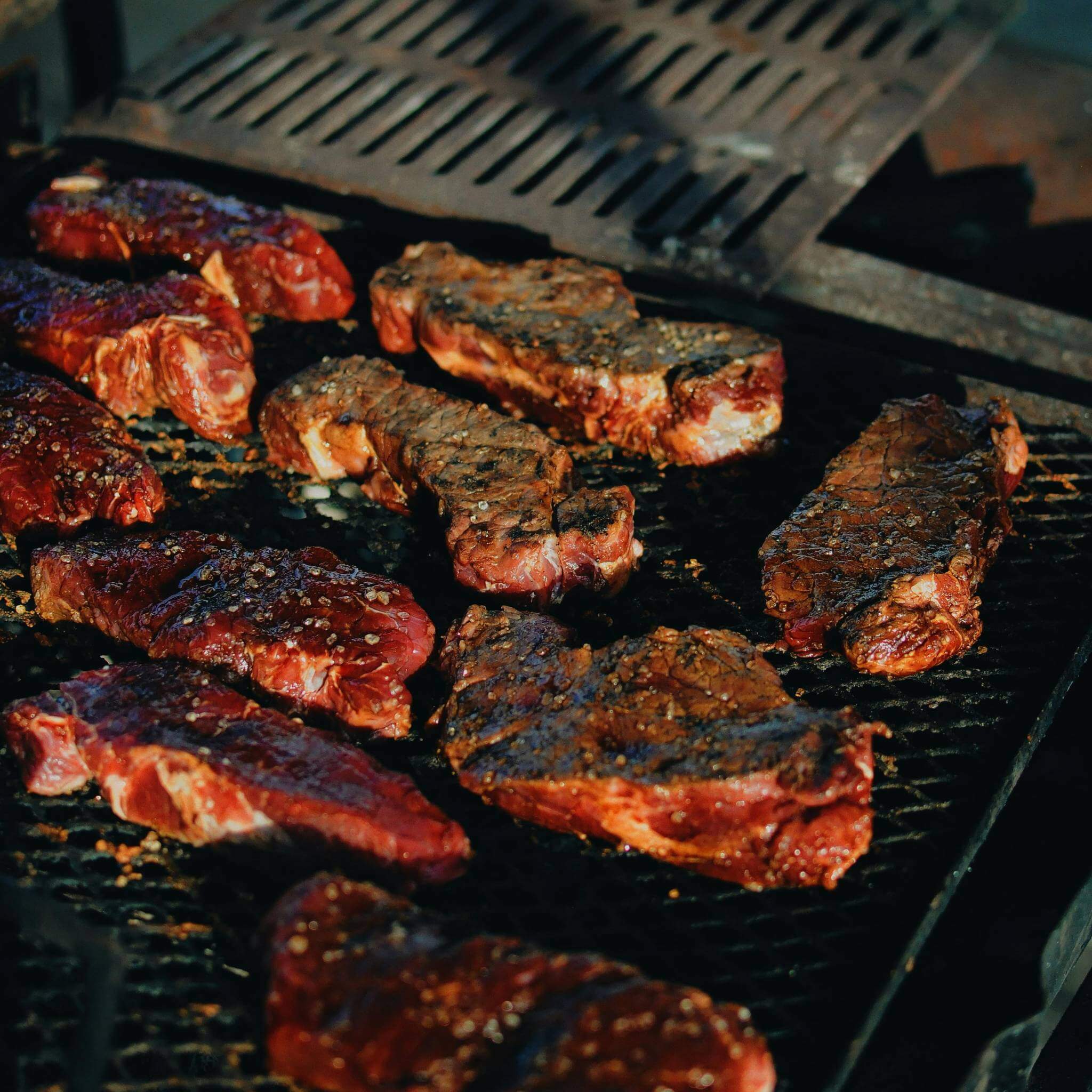 Grilled steaks on a braai with a smoky flavor, showcasing rich textures and seasoning.