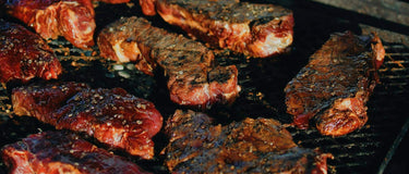Grilled steaks on a braai with a smoky flavor, showcasing rich textures and seasoning.