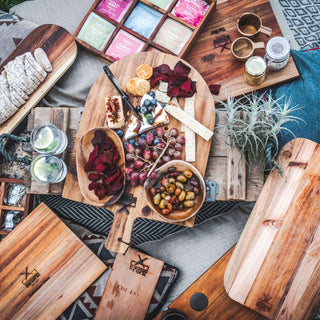 A beautifully arranged picnic spread featuring fruits, snacks, and drinks on wooden cutting boards.