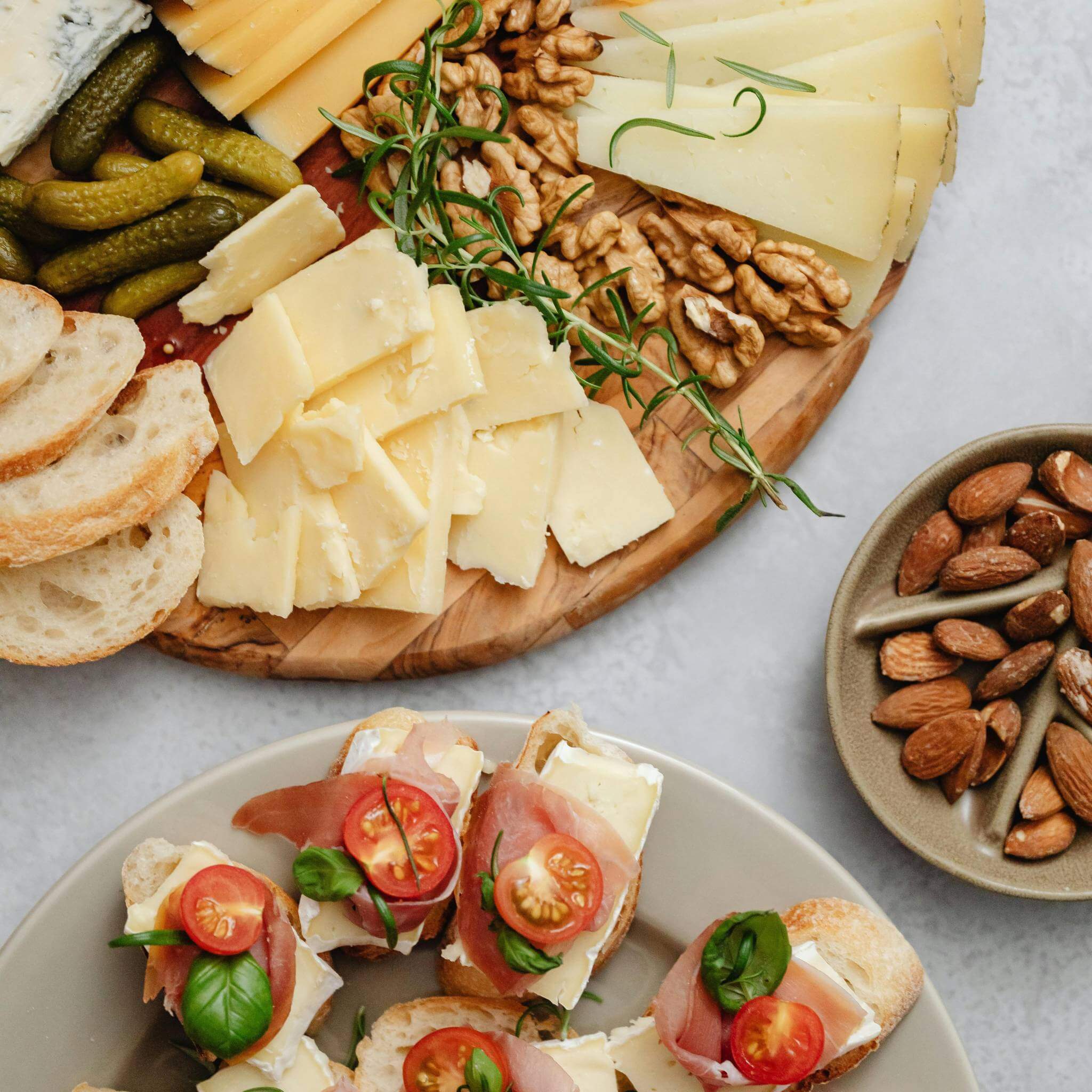 A beautifully arranged cheese board featuring various cheeses, bread, nuts, and pickles, perfect for gatherings.