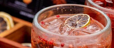 Refreshing cocktail served in a glass with ice and a lemon slice, highlighting vibrant flavors for a home happy hour.