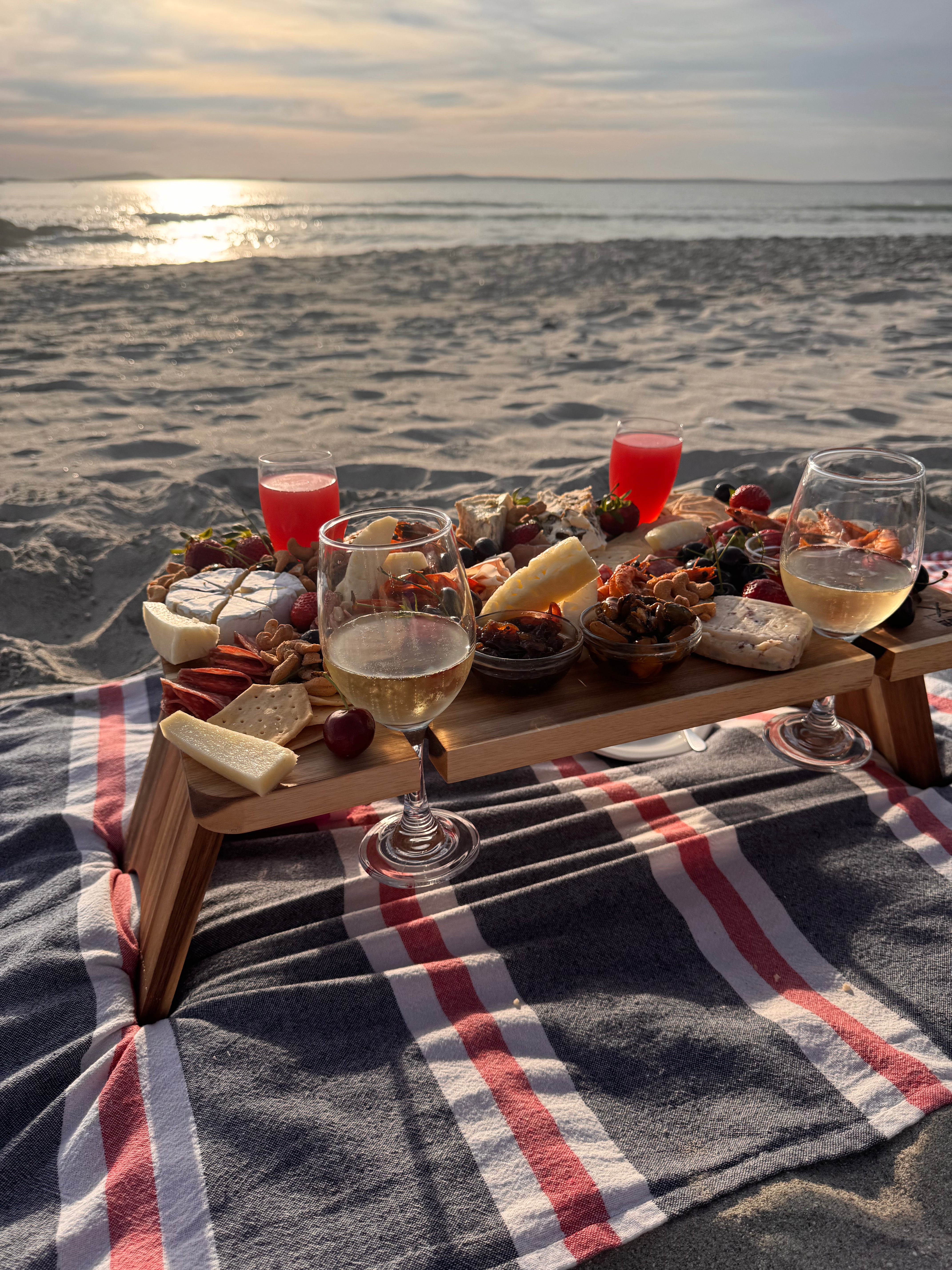 Picnic setup with food and drinks on a beach at sunset