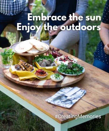 A beautiful outdoor dining setup featuring various dishes on a wooden table with a sunny ambiance.