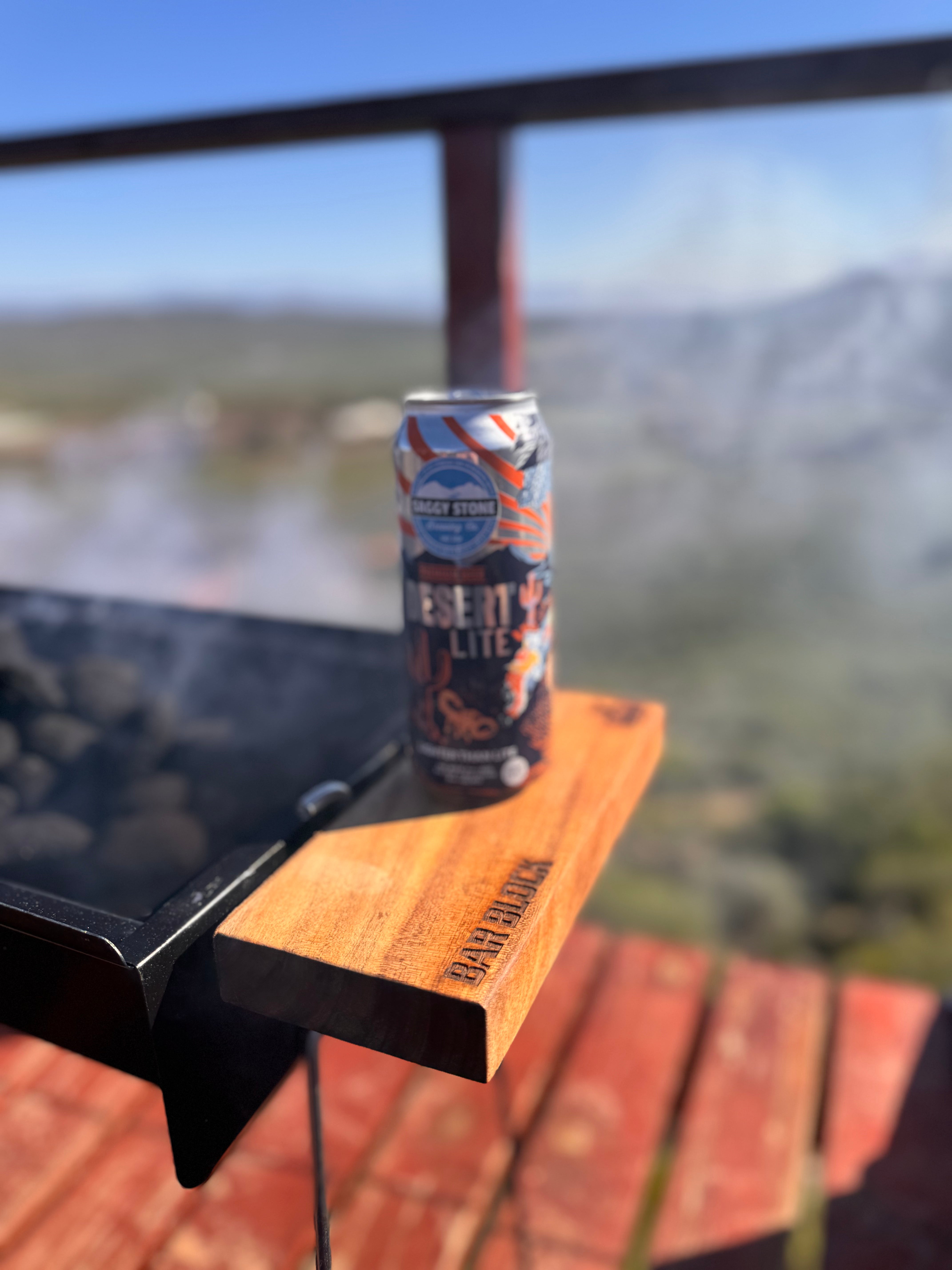 Desert Sun Lite beer can on a wooden ledge with a scenic background