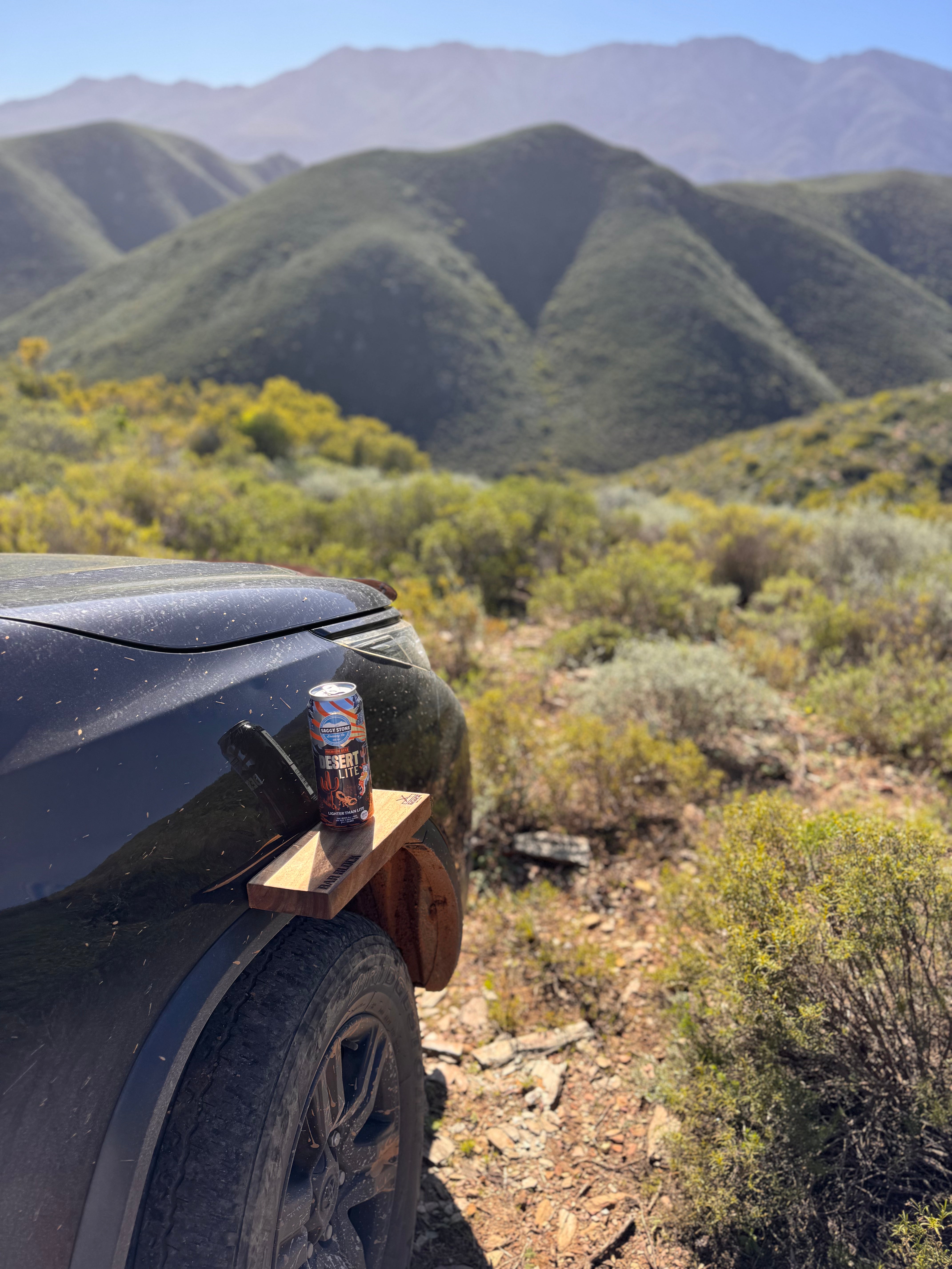 Can of beer on a car bumper with mountains