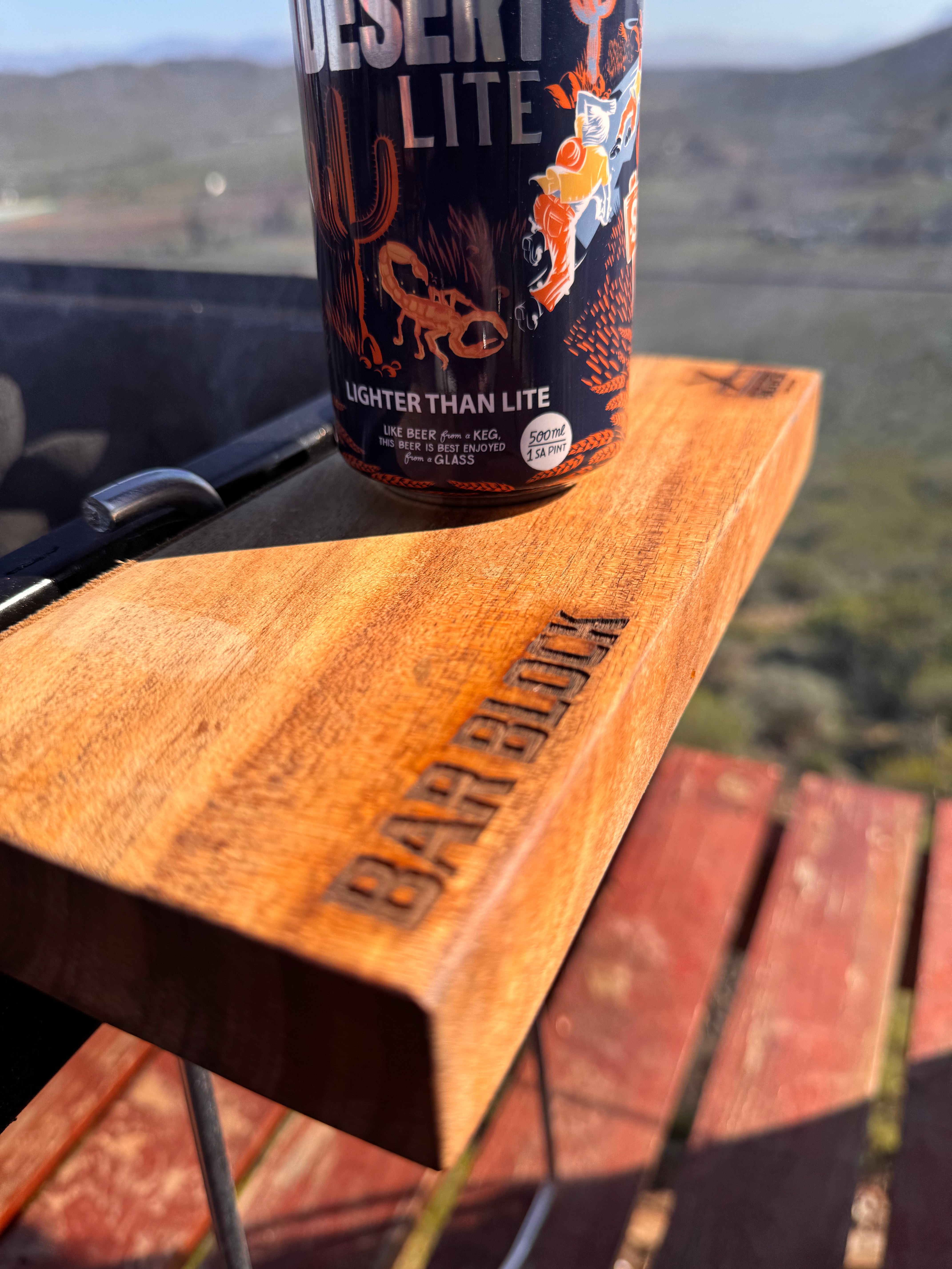 Desert Lite beer can on a wooden surface with a scenic background